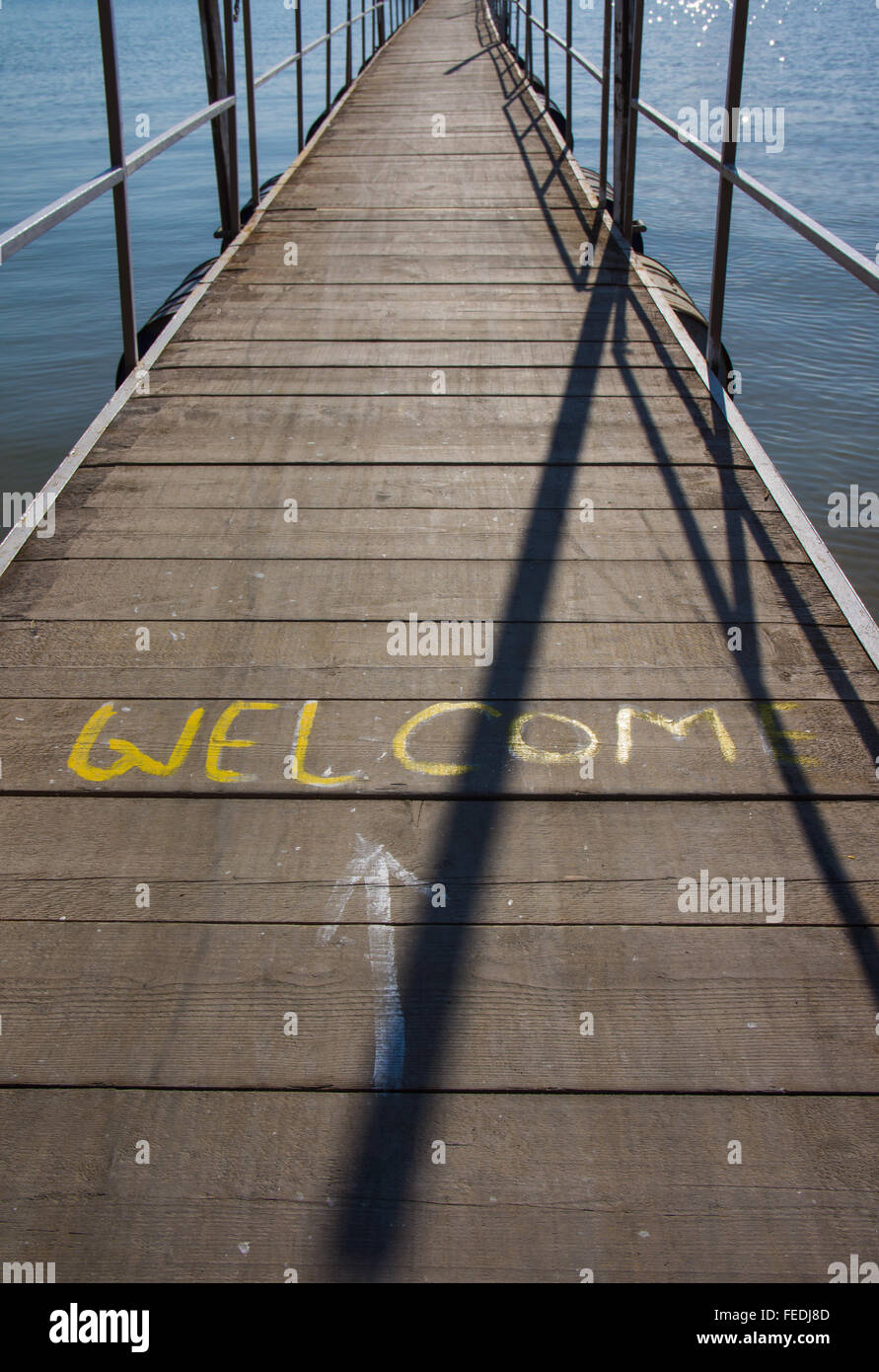 Segno di benvenuto dipinta su un pontile galleggiante con pavimento in legno. Foto Stock