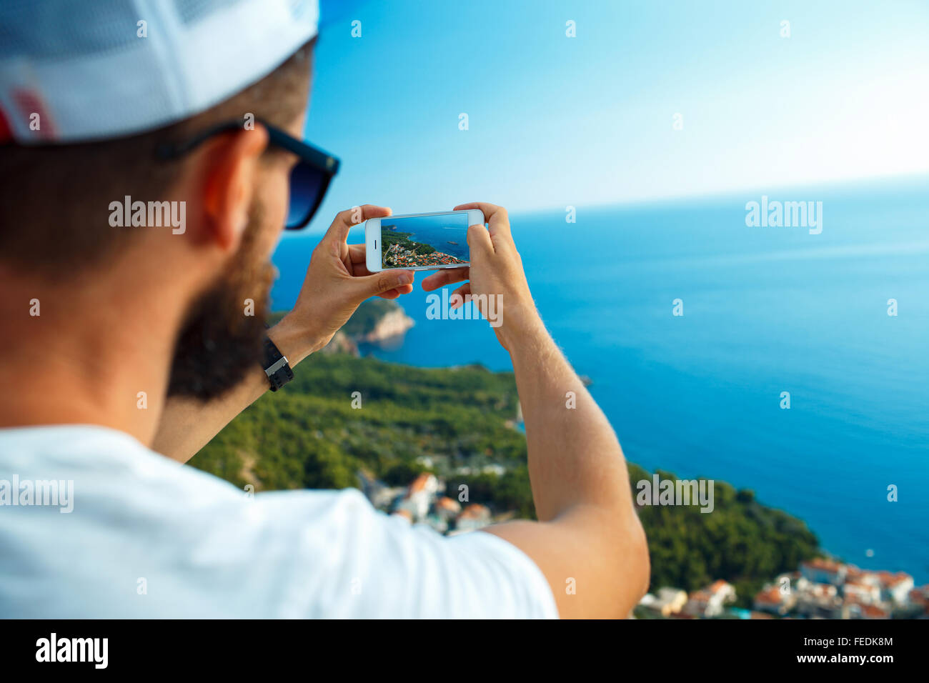 L uomo rende le foto da uno smartphone sullo sfondo del mare, mare adriatico, Montenegro, Balcani Foto Stock