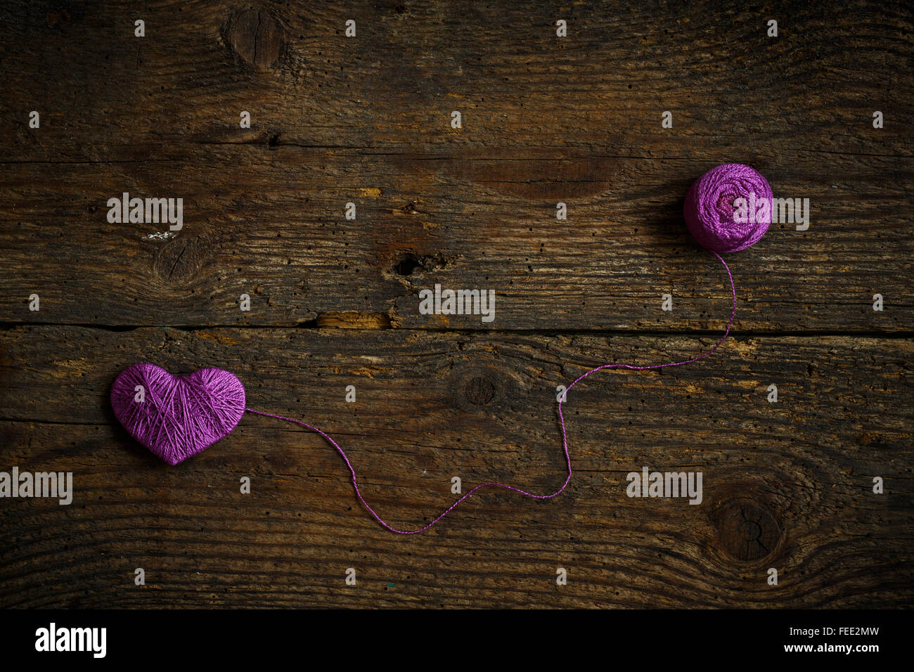 Cuore viola con una palla di filo sul vecchio squallido sfondo di legno. Immagine del giorno di San Valentino Foto Stock