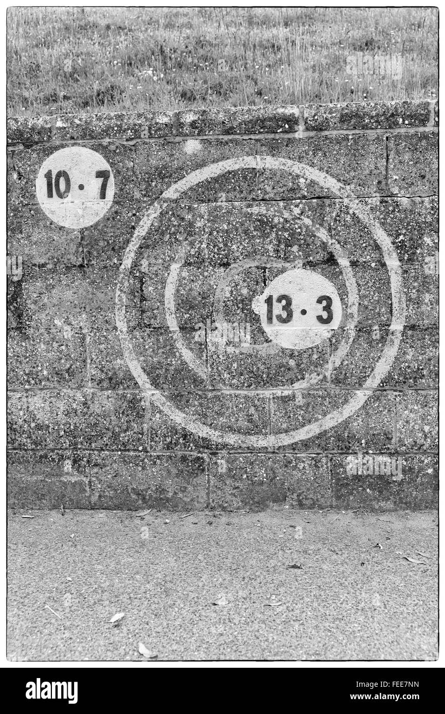 Una foto in bianco e nero di numeri in un cerchio verniciato sulla scura parete in muratura all'aperto in Europa Foto Stock