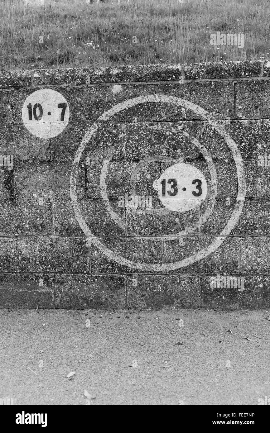 Una foto in bianco e nero di numeri in un cerchio verniciato sulla scura parete in muratura all'aperto in Europa Foto Stock