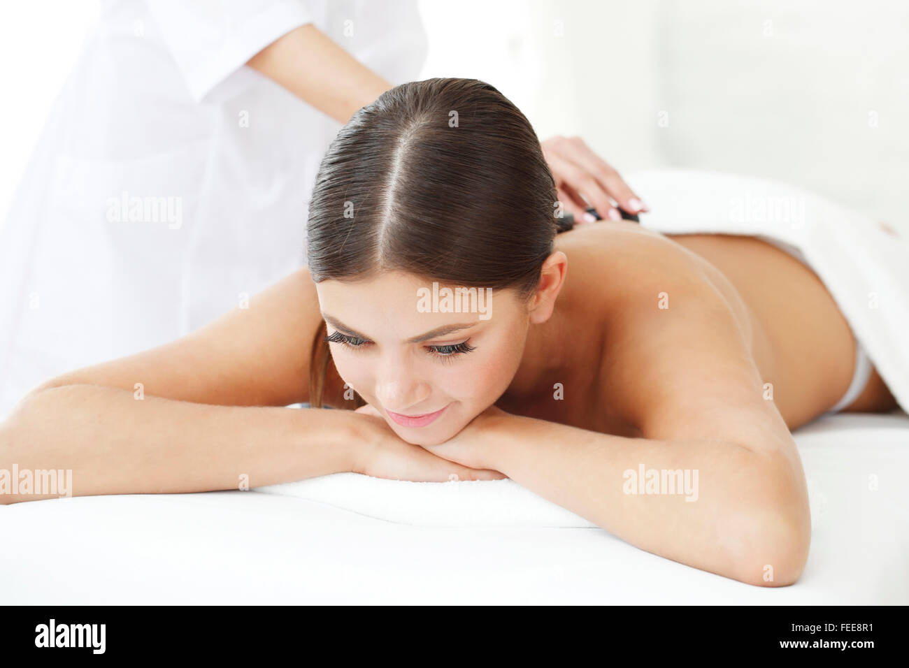 Giovane bella donna in spa come ottenere un massaggio con pietre calde Foto Stock