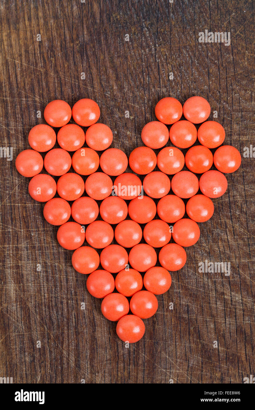 Cuore rosso con vitamine sulla tavola di legno. Foto Stock