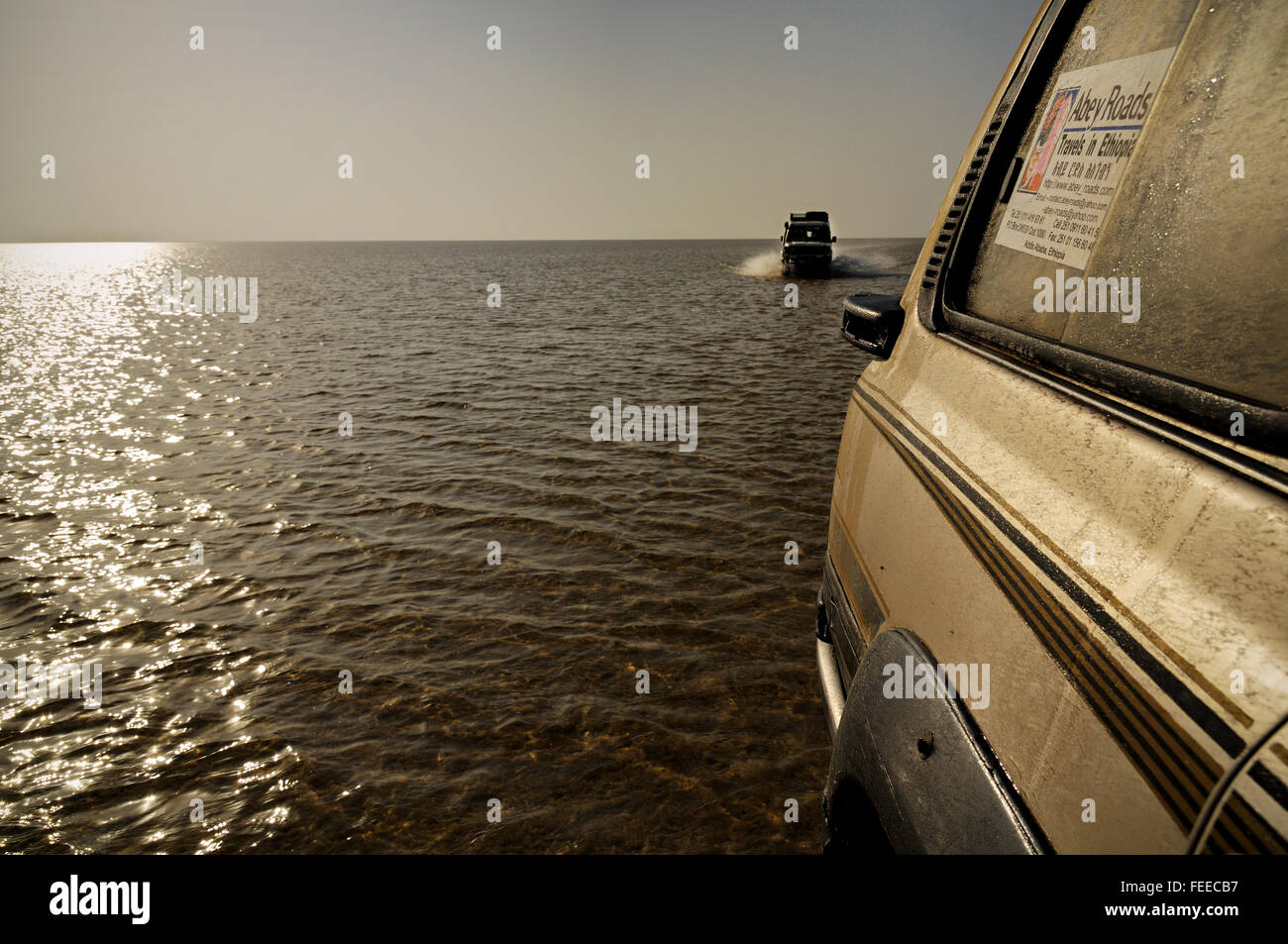 Due veicoli fuoristrada attraversando il basso lago d acqua Assale nella depressione di Danakil presso sunrise, regione di Afar, Etiopia Foto Stock