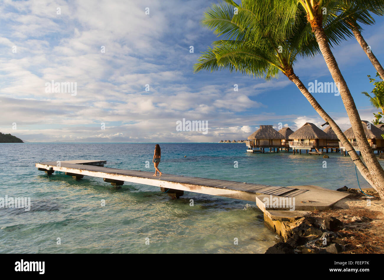 Donna che cammina sul molo con bungalow Overwater di Le Maitai Hotel, Bora Bora, Isole della Società, Polinesia Francese Foto Stock