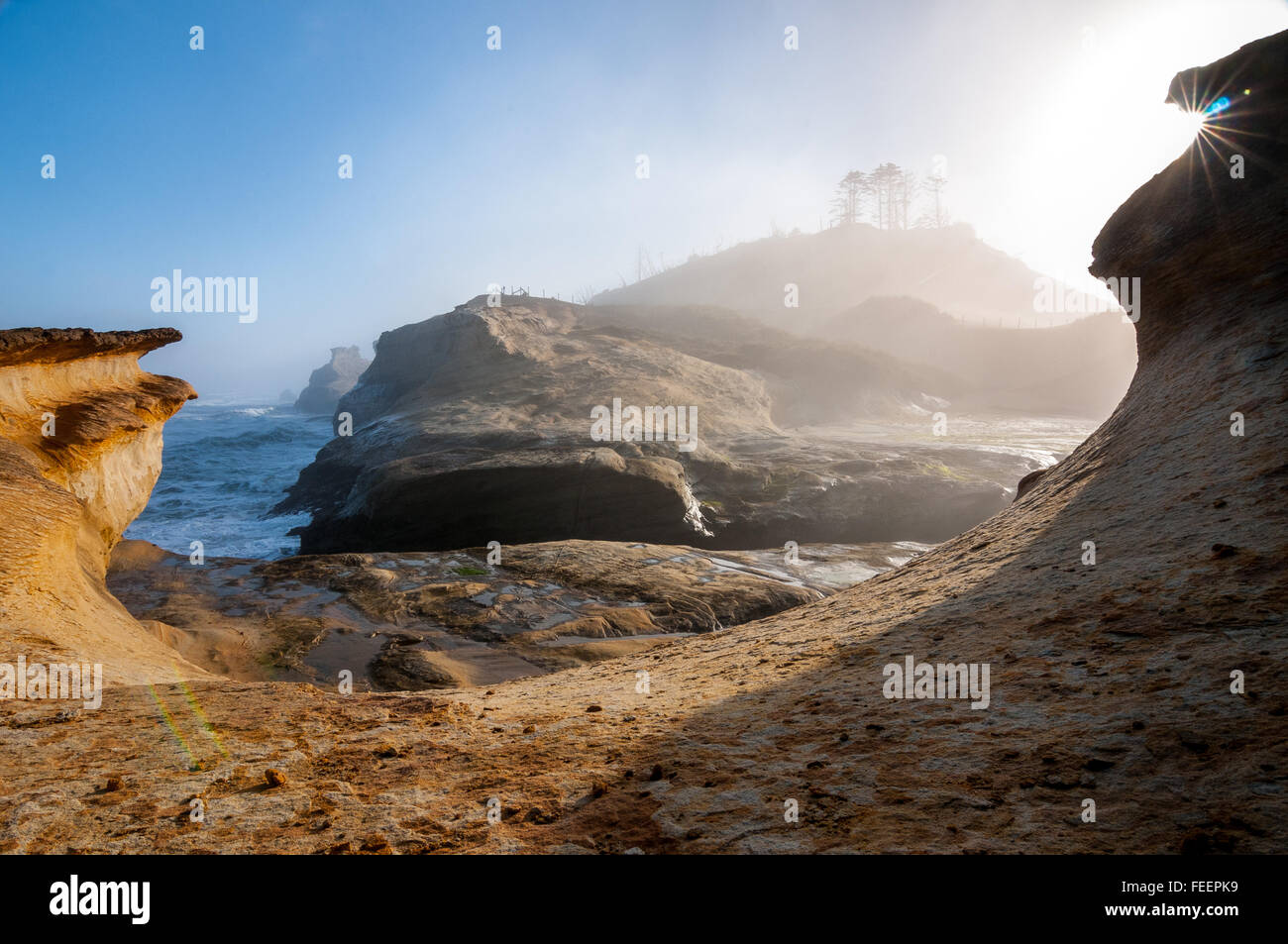 I picchi di sole fuori da dietro il labbro di una a forma di ciotola formazione di arenaria. Foto Stock