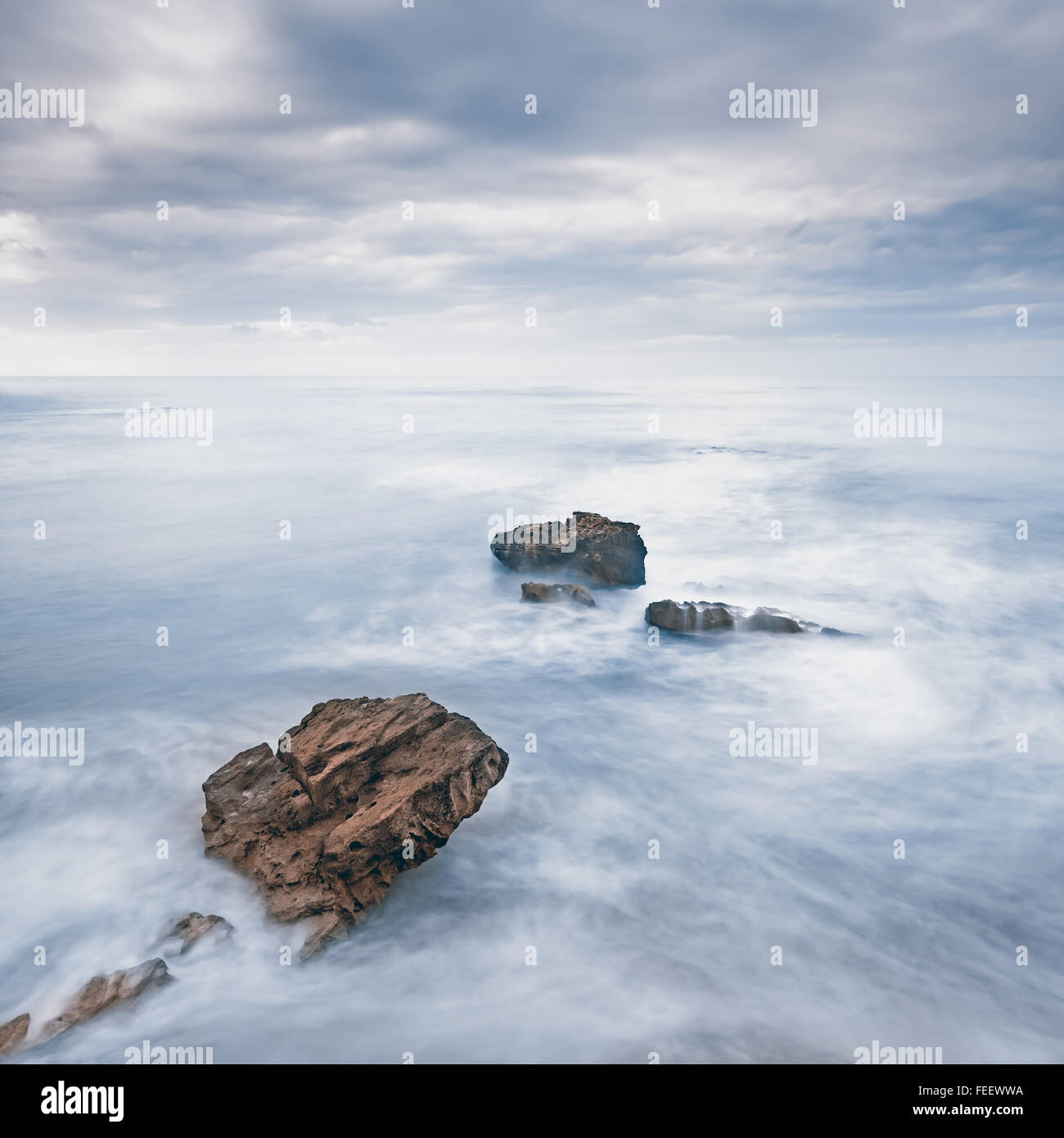 Le rocce in un blu oceano onde sotto il cielo nuvoloso di un cattivo tempo. Fotografie con lunghi tempi di esposizione Foto Stock