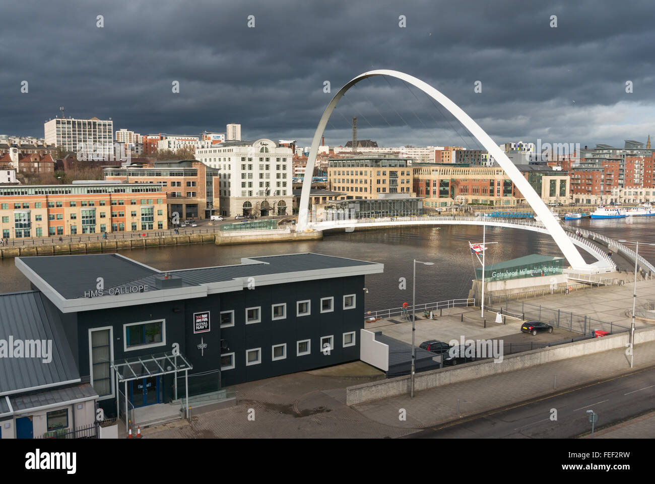 HMS Calliope e Gateshead Millennium Bridge con un cielo tempestoso su Newcastle upon Tyne dietro, North East England, Regno Unito Foto Stock