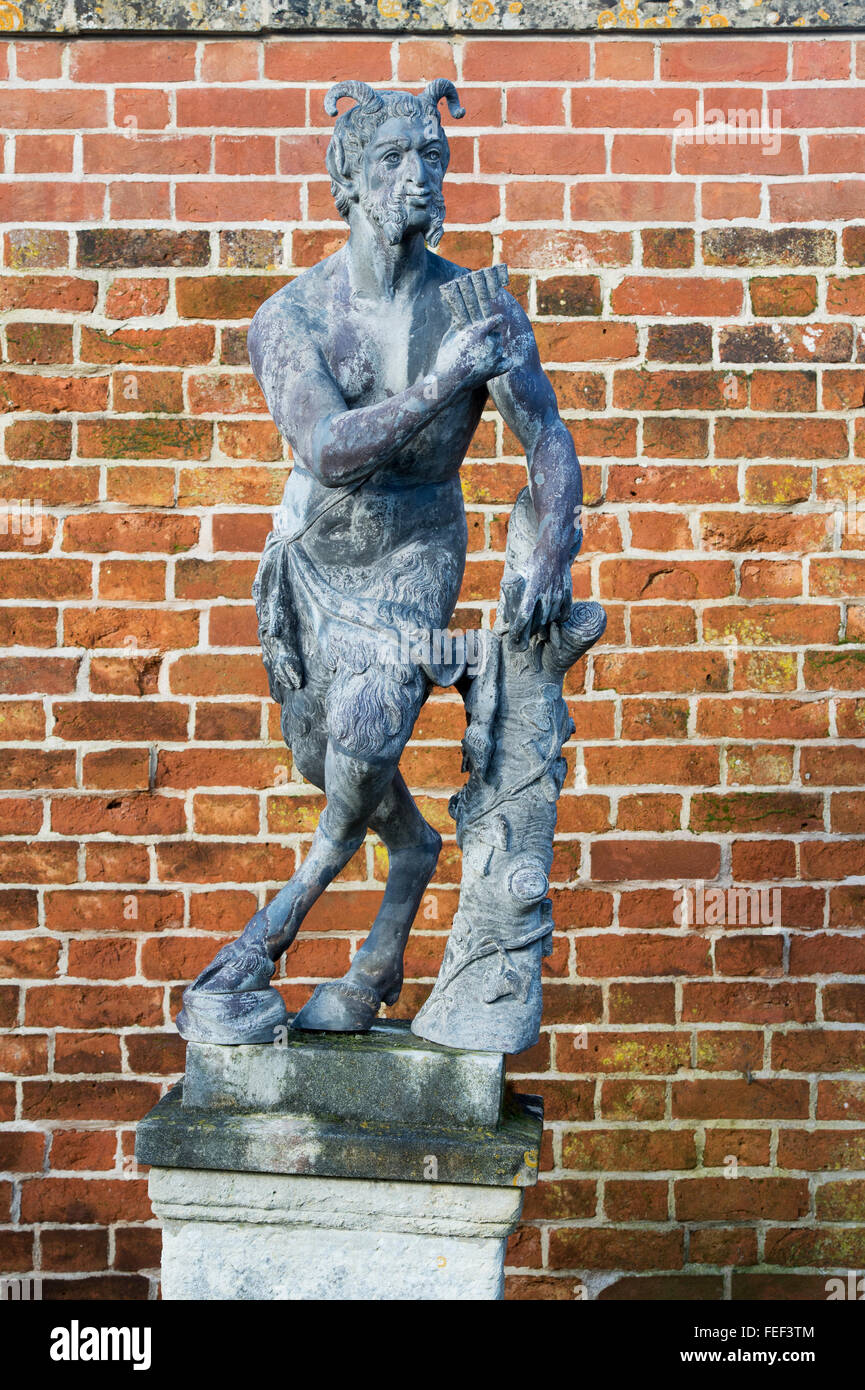 Statua di pan di fronte a un muro di mattoni a Painswick Rococo Gardens. Cotswolds, Gloucestershire, Regno Unito Foto Stock