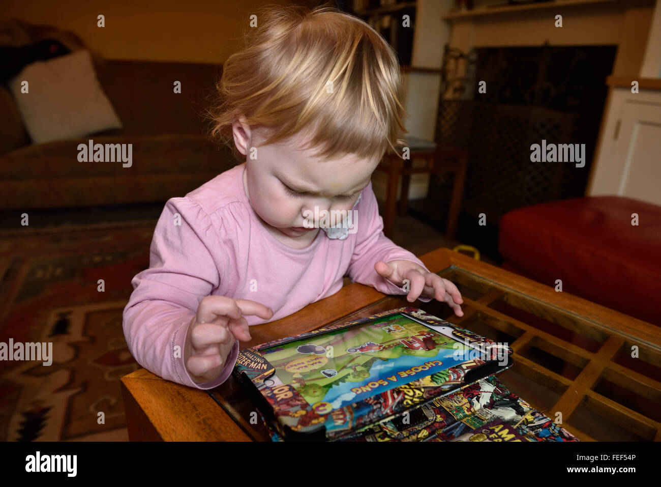 Un diciotto mesi concentrando toddler durante la riproduzione di un gioco su un ipad nella sua casa. Foto Stock