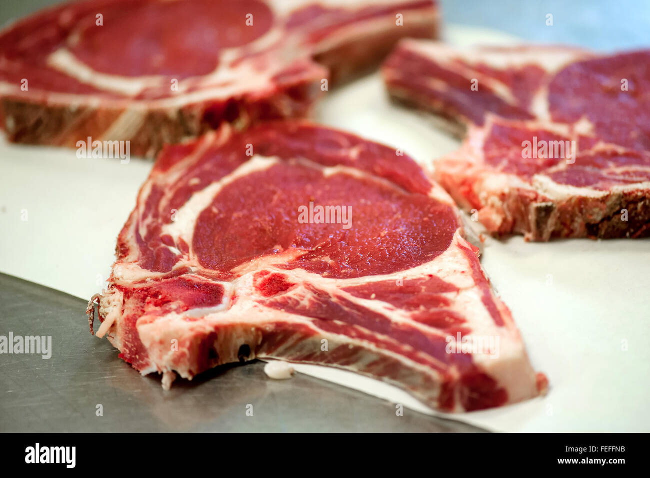 Fette di materie costola occhio bistecche di carne giacenti su un bancone in una macelleria pronti per la vendita Foto Stock