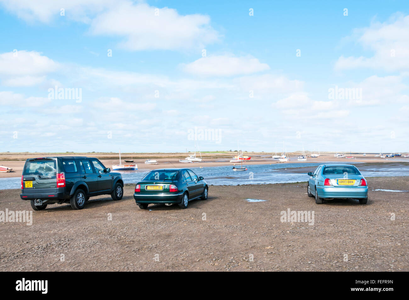 Vetture parcheggiate sul foreshore a Brancaster Staithe, Norfolk. Foto Stock