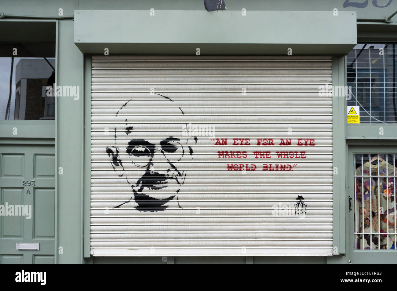 Un occhio per occhio rende cieco il mondo intero, la citazione di Gandhi come graffiti su un negozio otturatore. Foto Stock