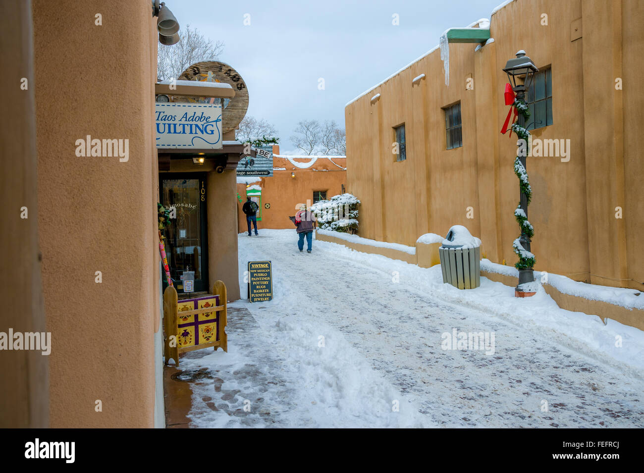 Una strada innevata tra edifici adobe a Taos, Nuovo Messico, US Foto Stock