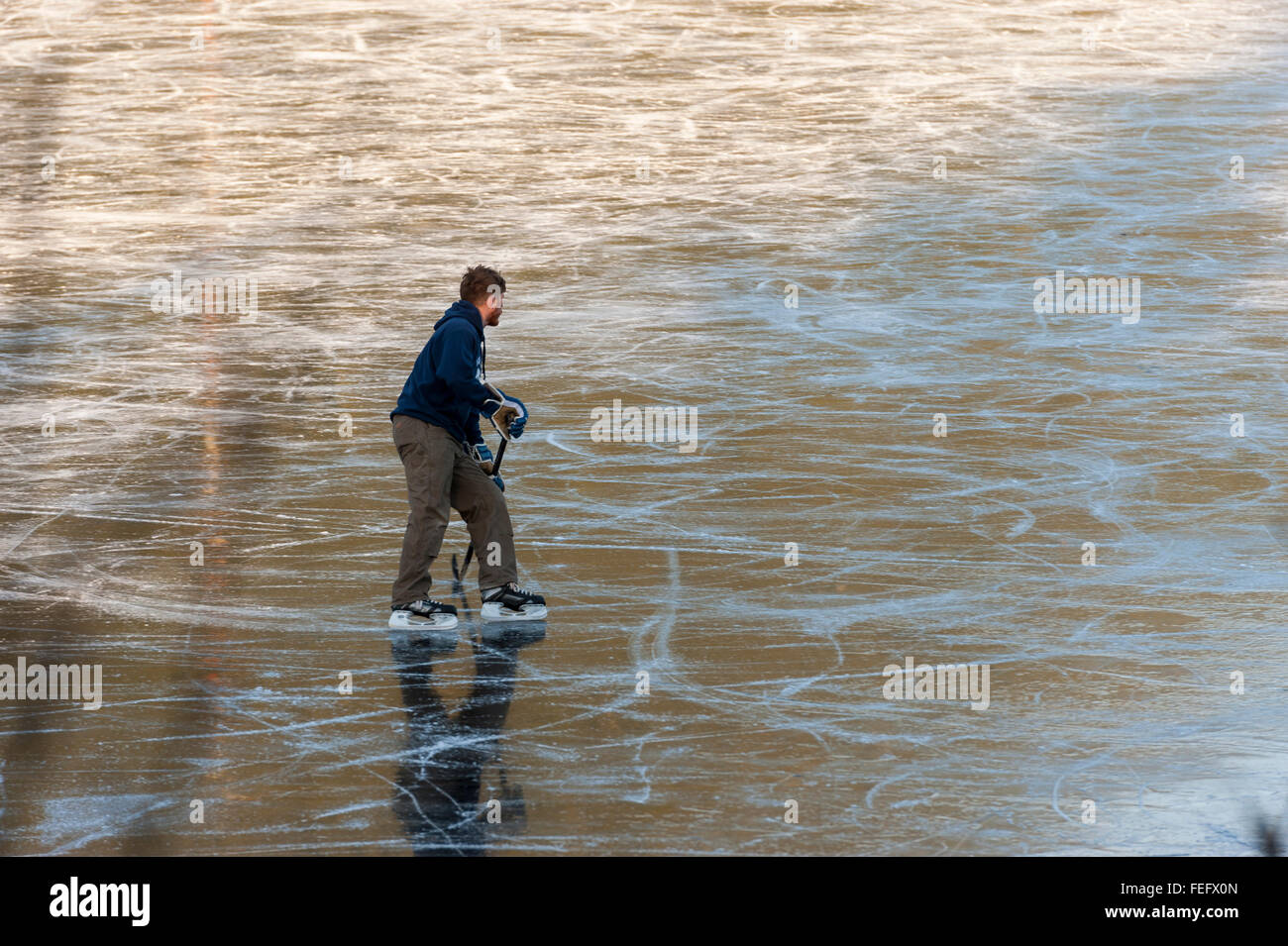 Uomo a giocare a hockey su Swan Lake di ghiaccio in Sitka, Alaska, Stati Uniti d'America. Fotografia di Jeffrey Wickett, fotografia NorthLight LLC, www. né Foto Stock