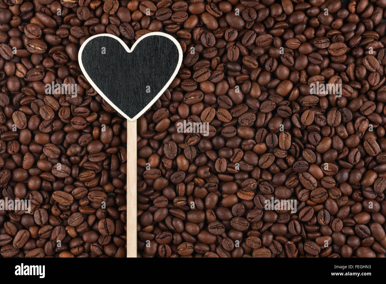 Il puntatore a forma di cuore si trova sul caffè in grani, con spazio per il testo Foto Stock