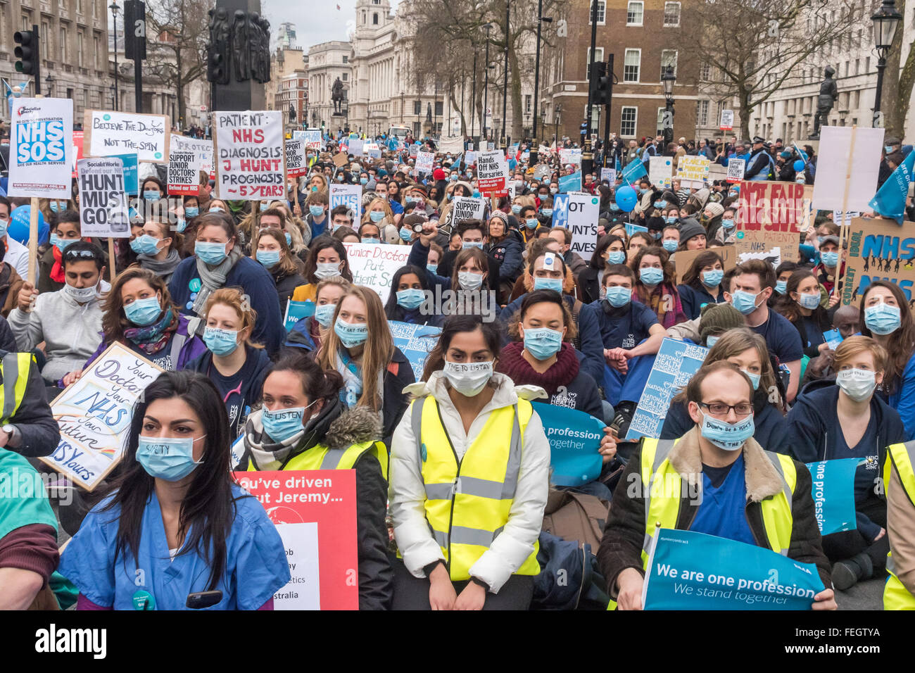 Londra, Regno Unito. Il 1 febbraio, 2016. Diverse migliaia di medici di sedersi indossando maschere chirurgiche in Whitehall a Downing St contro l'istituzione di nuovi contratti che dicono che distruggerà il NHS e rendono sicuri per i pazienti. NHS medici già opera 24/7 e accusano Jeremy Hunt di trarre in inganno il pubblico e i media. Peter Marshall / Alamy Live News Foto Stock