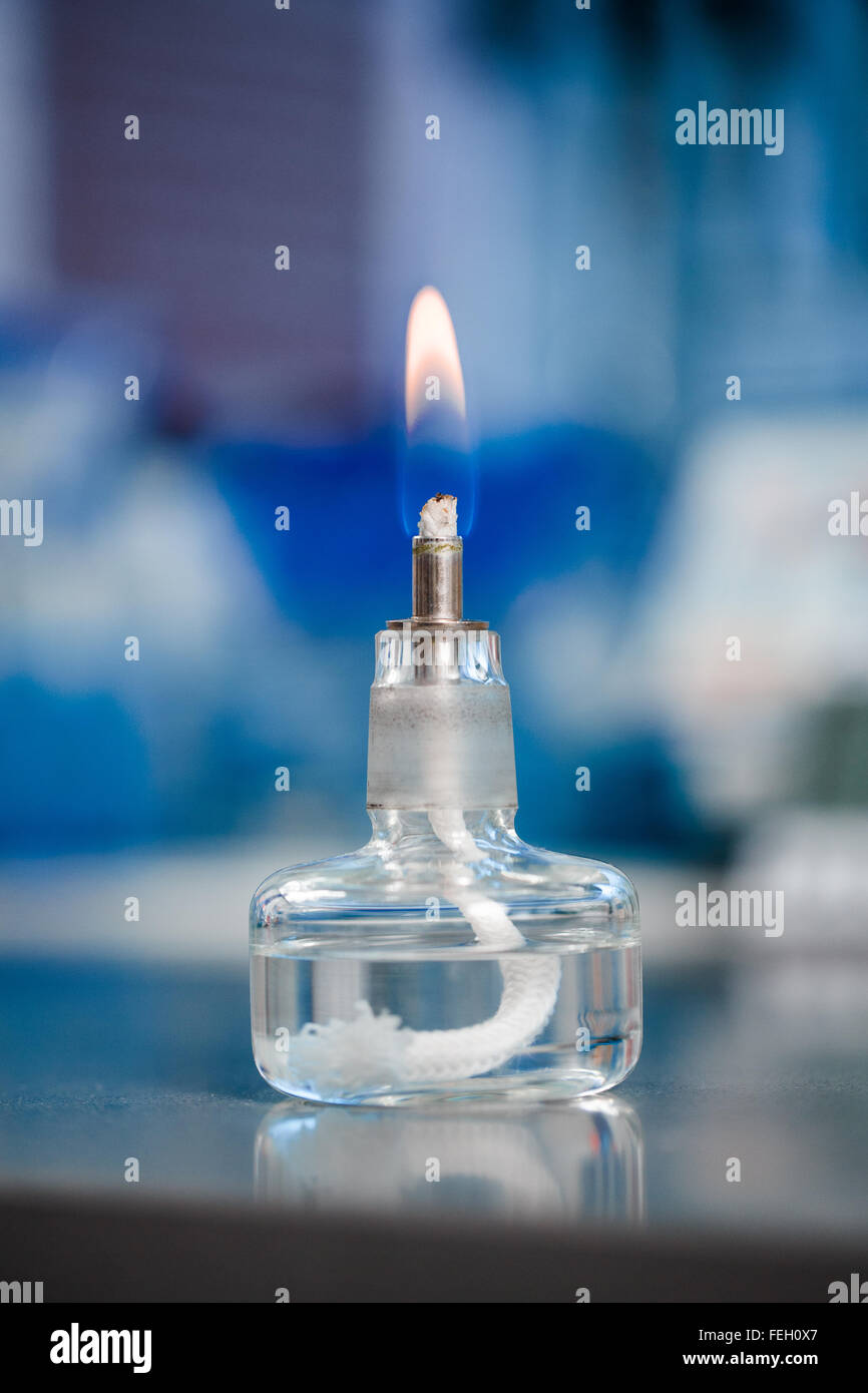 Il vetro piccolo bruciatore per esperimenti di chimica su sfondo blu Foto Stock