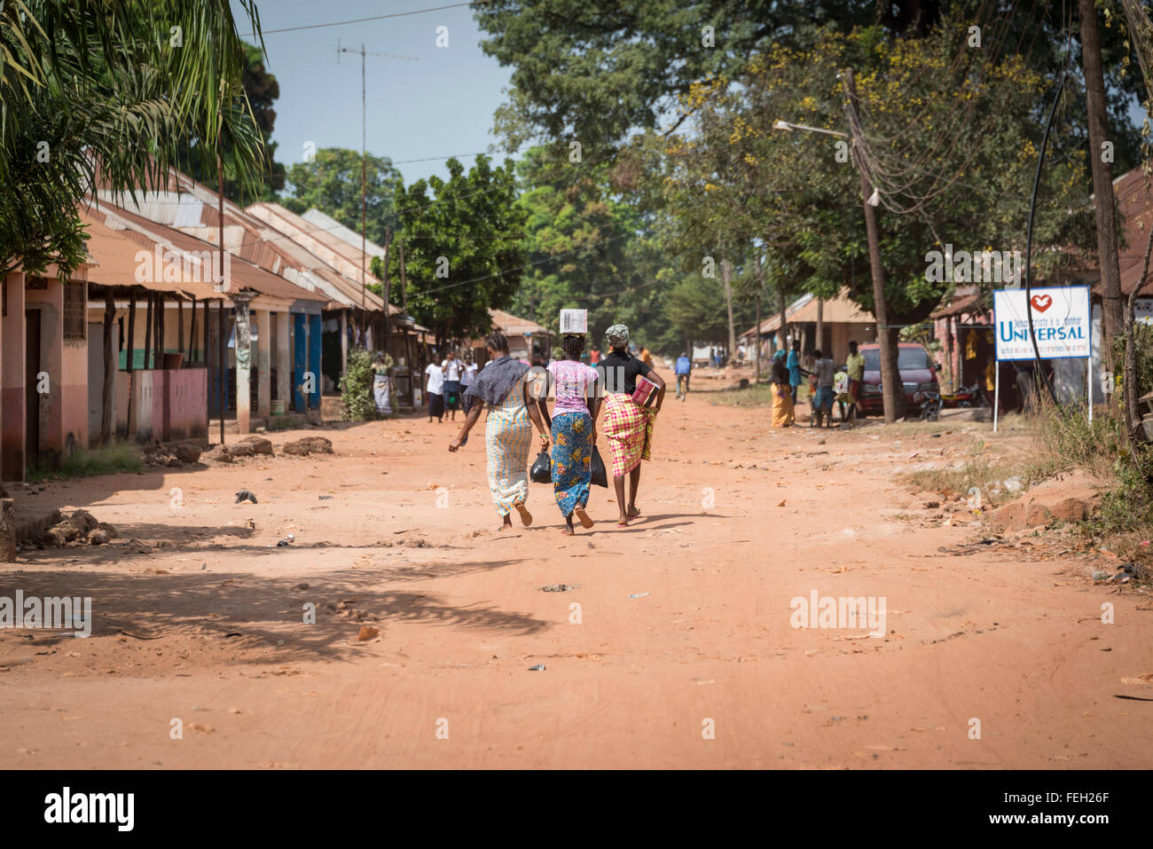 Gli abitanti di un villaggio a piedi giù per la strada non pavimentata in una regione del nord della Guinea Bissau città Foto Stock