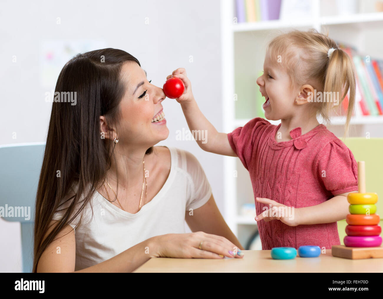 Sorridendo la madre e il bambino figlia in vivaio, felice e stare insieme Foto Stock