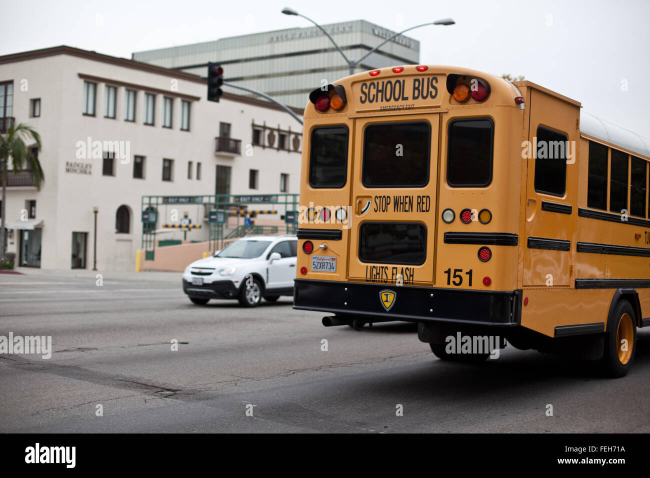 Vista della strada in Beverly Hills, CA con il dorso del bus di scuola e la parte anteriore della vettura bianca in shot. Foto Stock