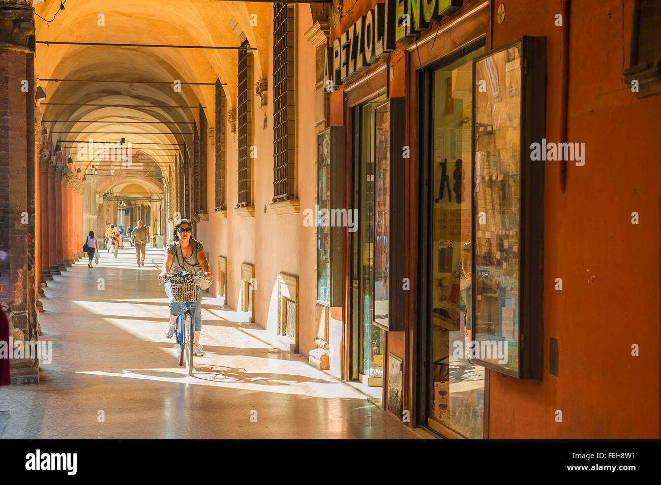 Bologna centro storico, vista in estate di una donna in bicicletta sotto un portico medievale in Strada Maggiore a Bologna città vecchia (Centro Storico), Italia. Foto Stock