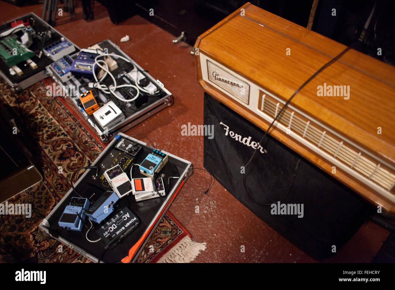 Tre schede del pedale sul pavimento studio accanto al parafango vintage amp. Studio pavimento è dipinta con stile persiano rug sulla parte superiore. Foto Stock