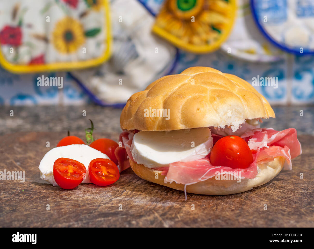 Macro di sandwich al prosciutto, pomodorini e mozzarella su un tagliere di legno Foto Stock