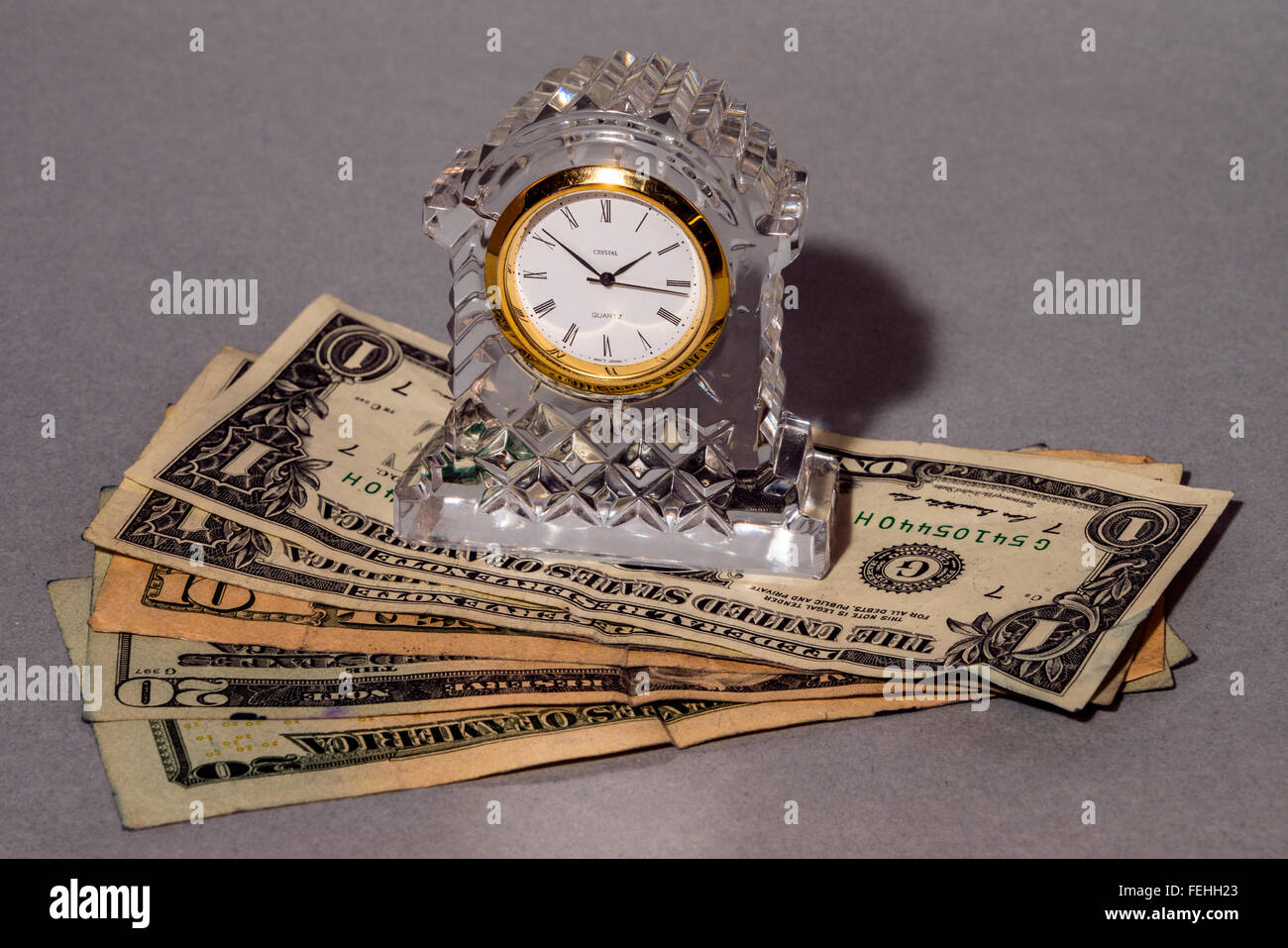 Concettualmente tempo significa denaro che mostra un orologio di cristallo e dollaro-fatture Foto Stock