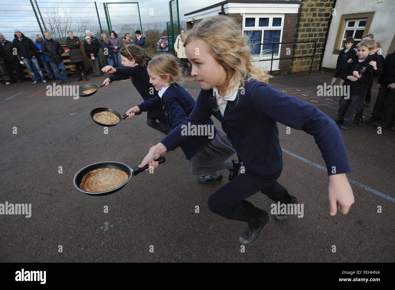 La scuola dei bambini godendo di un pancake race. Foto Stock