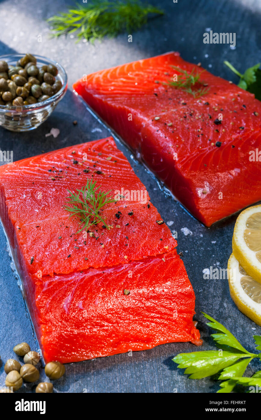 Due pezzi di materie di salmoni selvatici bistecca di pesce con il limone, i capperi e le erbe aromatiche, pronto a cucinare Foto Stock