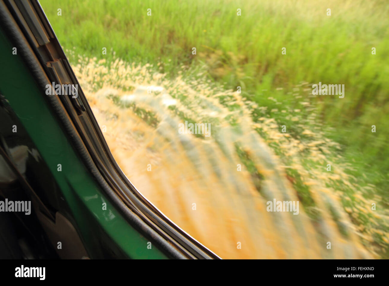 Guardando fuori dalla finestra come un safari carrello aziona attraverso una pozza di fango creando una splash Foto Stock