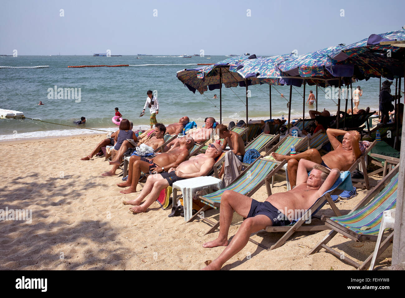 Persone che prendono il sole. Gruppo di turisti maschi occidentali maturi che prendono il sole su una spiaggia tropicale tailandese. Pattaya Thailandia turismo S. E. Asia Foto Stock