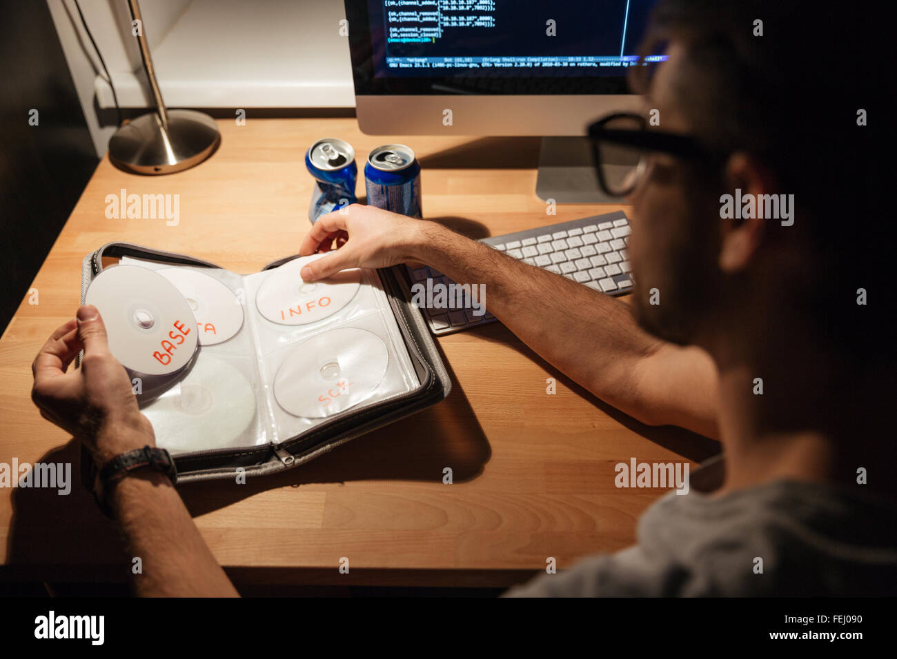 Bel giovane programmatori che utilizzano il computer a casa e la scelta di CD con dati Foto Stock
