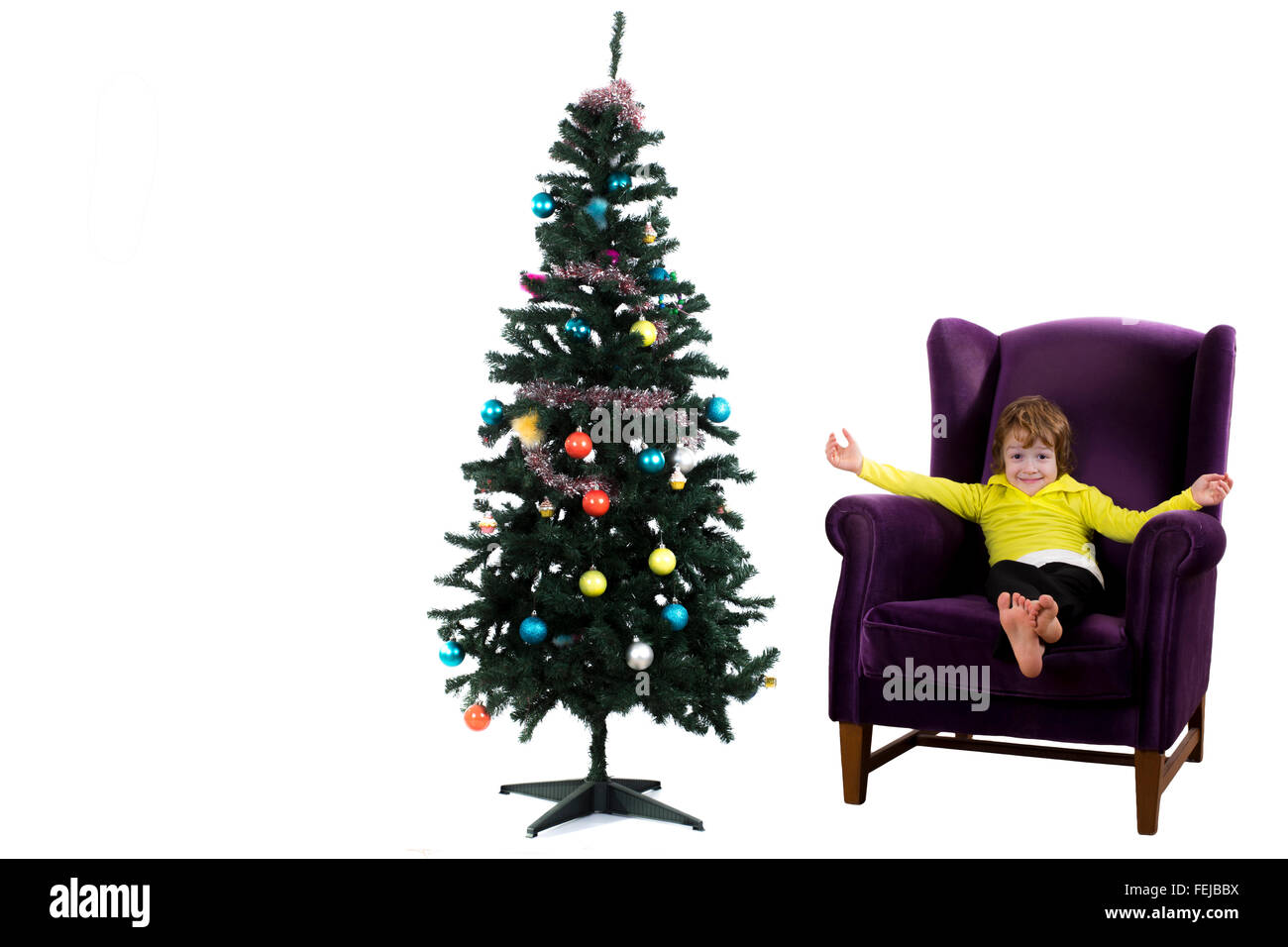 Felice capelli rossi bambino seduto sulla poltrona viola accanto a albero di Natale Foto Stock