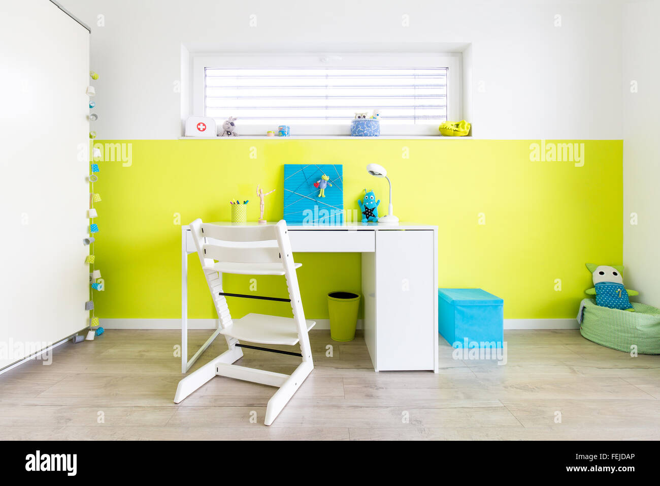 Colorata sala giochi per bambini con scrivania e un muro verde Foto Stock