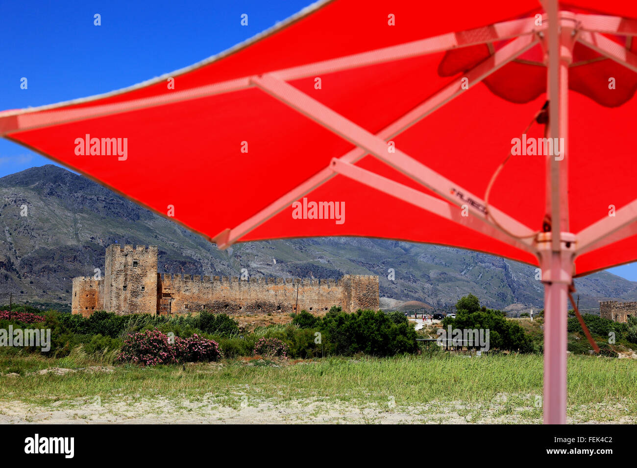 Creta, rosso di ombrelloni e la fortezza di Frangokastello sulla costa sud dell'isola mediterranea Foto Stock