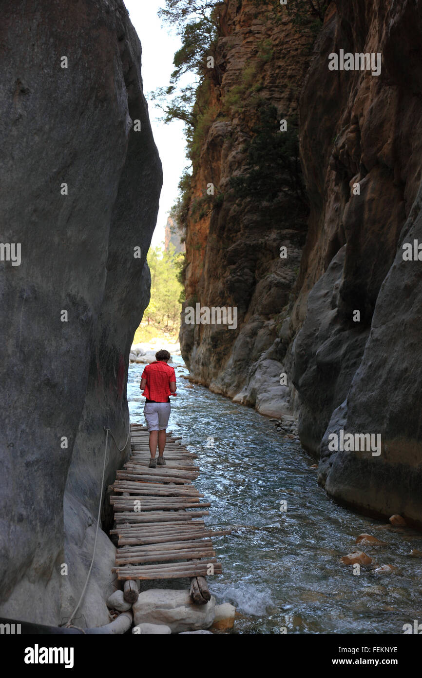 Creta, scenario in Samaria gulch, donna viene eseguito su una piccola passerella in legno accanto il torrente dal gulch, il cancello di ferro Foto Stock