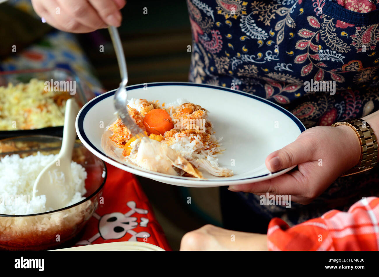 Una donna mette il cibo sulla sua piastra ad un buffet a parte Foto Stock