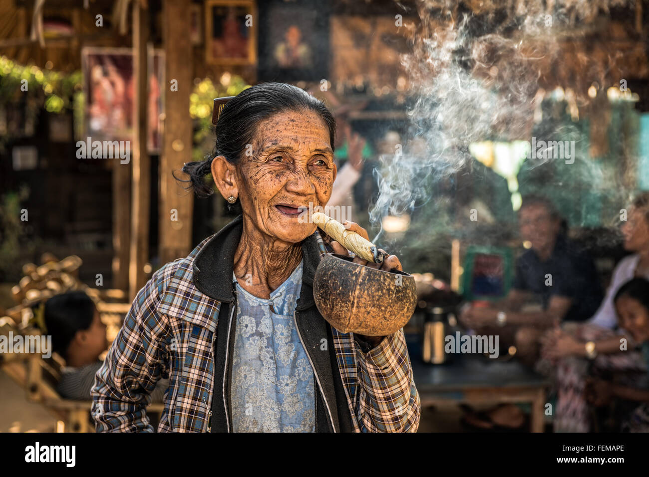 Felice e vecchia donna rugosa fuma una grande cheroot sigaro in pubblico Foto Stock
