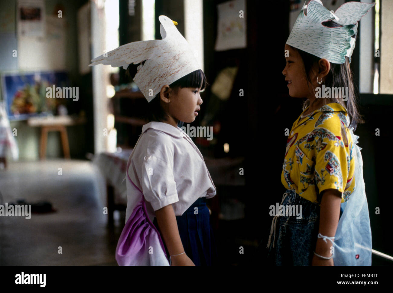 2 giovani ragazze della scuola con i loro splendidi fatti a mano e disegnati per i cappelli di carta con uccelli sulla parte anteriore a una scuola di villaggio in Laos Foto Stock