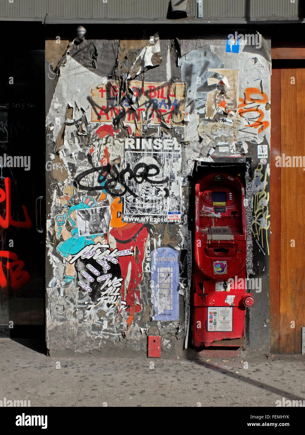 Un ATM nel mezzo di una parete con graffiti, adesivi e tagging on Rivington Street off Essex sulla Lower East Side di Manhattan, New York Foto Stock
