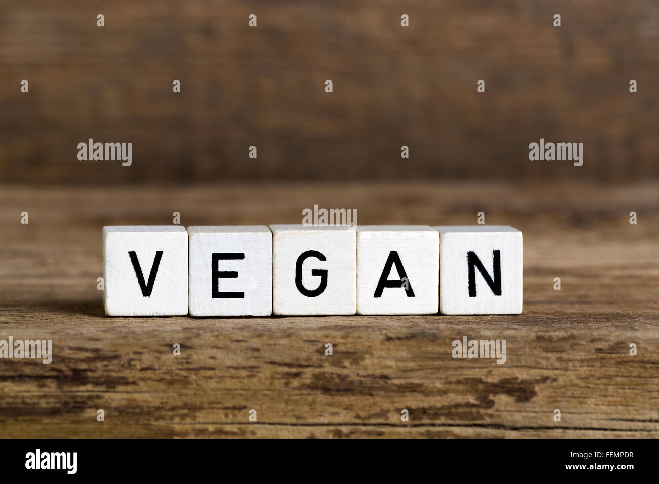 La parola scritta vegana in cubi su sfondo di legno Foto Stock