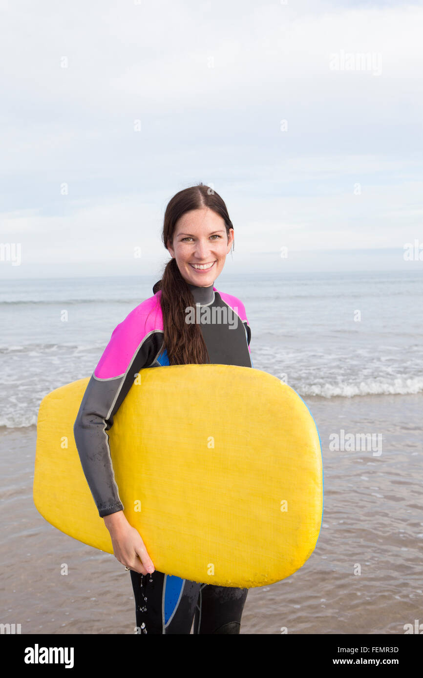 Donna in posa sulla spiaggia in una muta con un corpo stampato. Foto Stock
