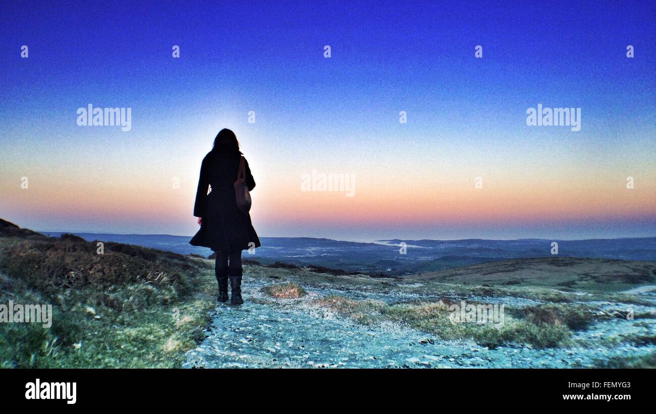 Vista posteriore della donna in piedi contro il cielo drammatico Foto Stock