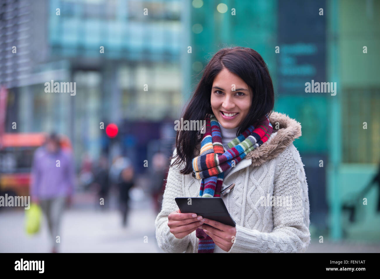Giovane donna in città con uno smartphone. Lei è sorridente alla fotocamera. Foto Stock