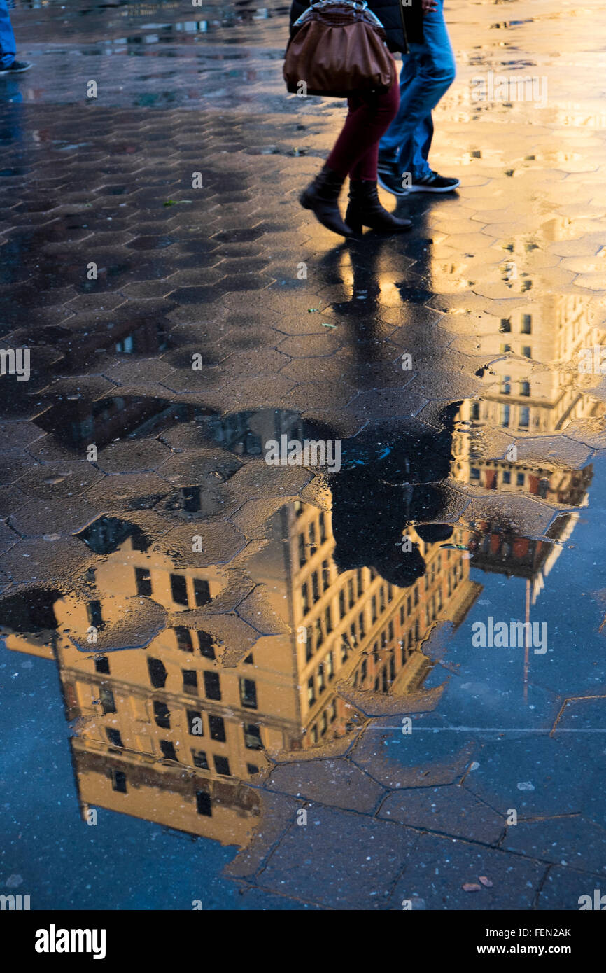 La riflessione in acqua di edifici e persone che camminano in Union Square, New York, Stati Uniti d'America Foto Stock