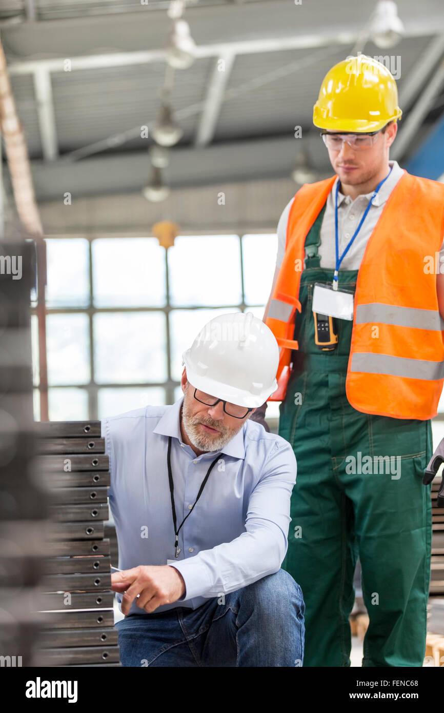 Ingegnere spiegando le parti in acciaio al lavoratore in fabbrica Foto Stock