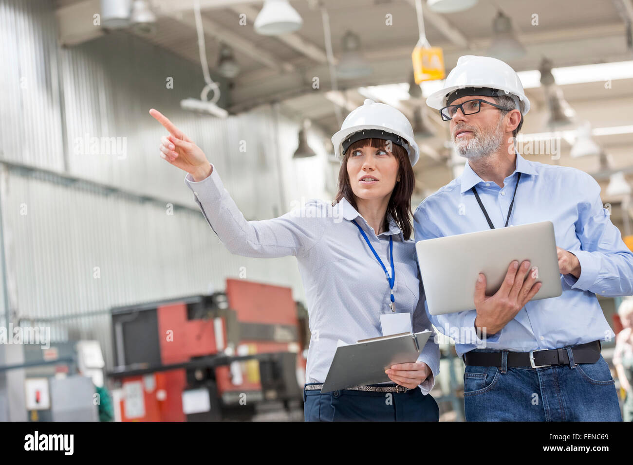 Ingegneri con laptop e appunti rivolti in fabbrica Foto Stock