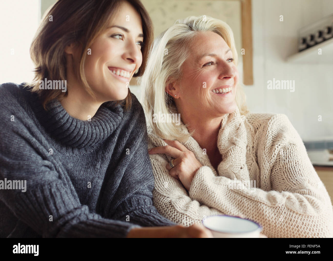 Sorridente madre e figlia in maglioni guardando lontano Foto Stock